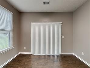 spare room with wood finished floors, baseboards, and visible vents