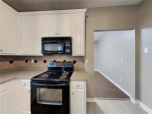 kitchen featuring decorative backsplash, light countertops, white cabinetry, and black appliances