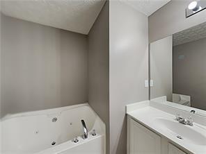full bath featuring a textured ceiling, a tub with jets, and vanity