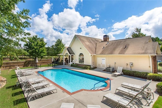 pool with a patio area, central air condition unit, and fence