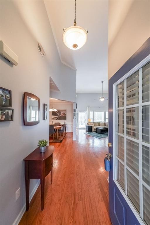 hallway with light wood-style floors, baseboards, and a wall mounted AC