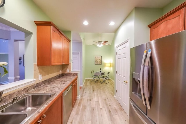 kitchen with light wood-type flooring, a ceiling fan, a sink, appliances with stainless steel finishes, and decorative backsplash