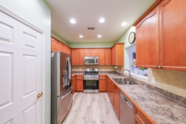 kitchen featuring visible vents, a sink, backsplash, light wood-style floors, and appliances with stainless steel finishes