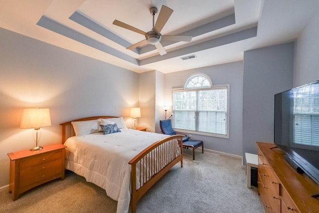 bedroom with light carpet, visible vents, baseboards, and a tray ceiling