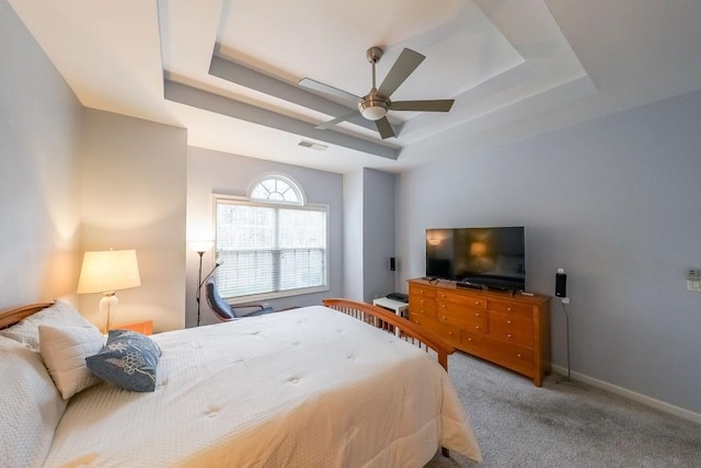 bedroom featuring a tray ceiling, carpet floors, baseboards, and visible vents