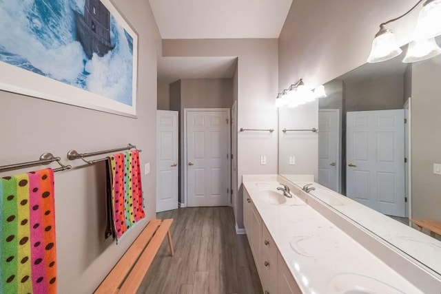 full bath featuring double vanity, wood finished floors, and a sink