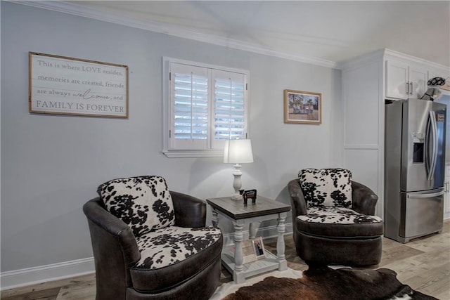 sitting room featuring crown molding, light wood-style flooring, and baseboards