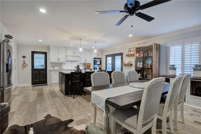 dining room featuring ceiling fan, baseboards, light wood finished floors, ornamental molding, and recessed lighting