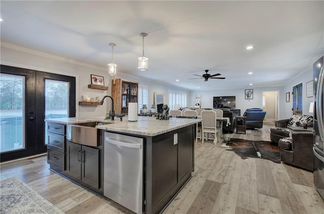 kitchen with a ceiling fan, stainless steel dishwasher, a sink, open floor plan, and light wood-style floors