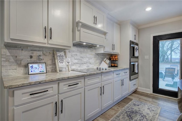 kitchen with crown molding, light stone countertops, light wood-type flooring, black electric cooktop, and white cabinets