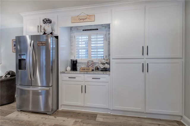 kitchen with stainless steel fridge, ornamental molding, light wood-style floors, and white cabinetry
