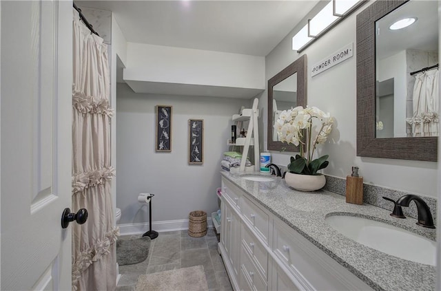 bathroom with baseboards, a sink, and double vanity