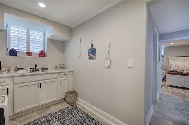 interior space featuring baseboards, a sink, and recessed lighting