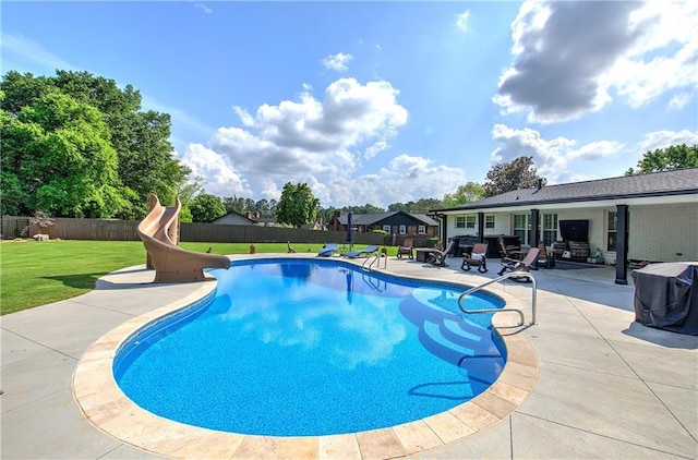 view of swimming pool with a lawn, fence, a fenced in pool, a patio, and a water slide