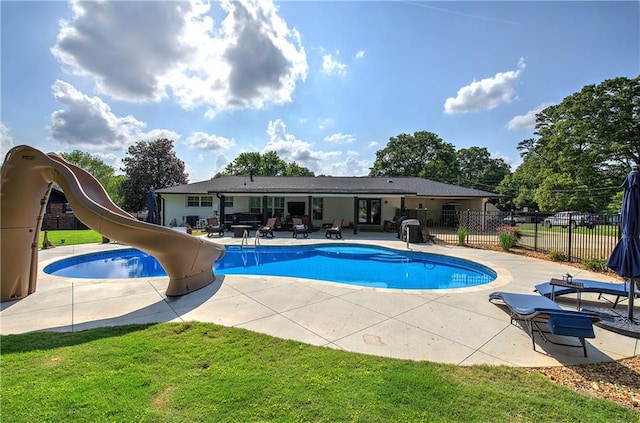 view of swimming pool featuring fence, a water slide, a fenced in pool, a patio area, and a lawn