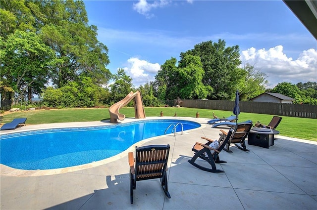 view of pool with a yard, fence, a water slide, and a patio