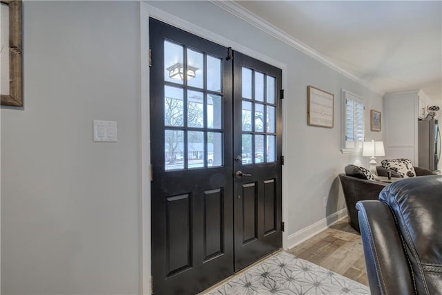 foyer featuring crown molding, baseboards, french doors, and light wood-type flooring