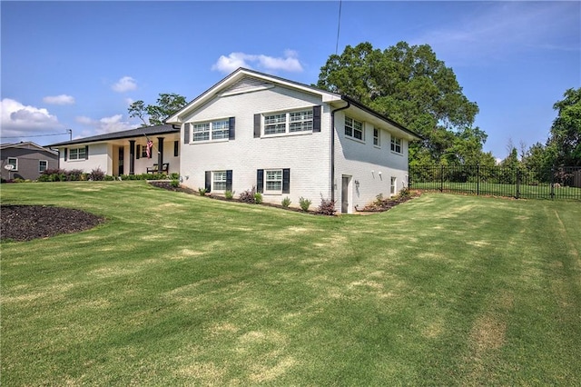 tri-level home featuring brick siding, a front lawn, and fence