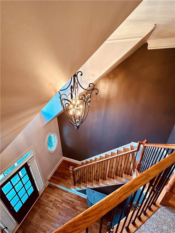 staircase with visible vents, baseboards, a notable chandelier, and wood finished floors