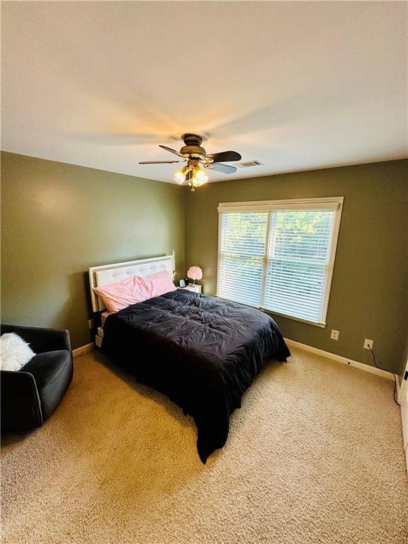 carpeted bedroom with visible vents, a ceiling fan, and baseboards