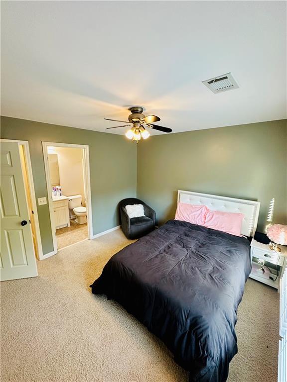 bedroom with visible vents, ceiling fan, baseboards, light carpet, and ensuite bathroom