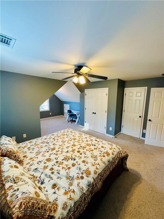 bedroom with visible vents, ceiling fan, baseboards, lofted ceiling, and light carpet