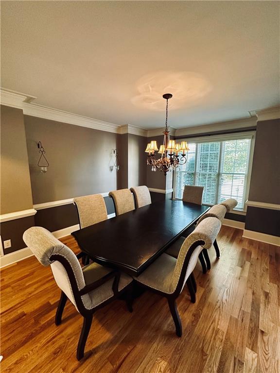 dining room featuring crown molding, a notable chandelier, wood finished floors, and baseboards