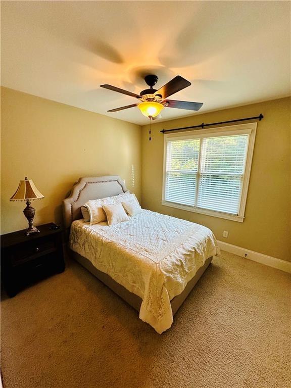 bedroom featuring baseboards, light colored carpet, and a ceiling fan