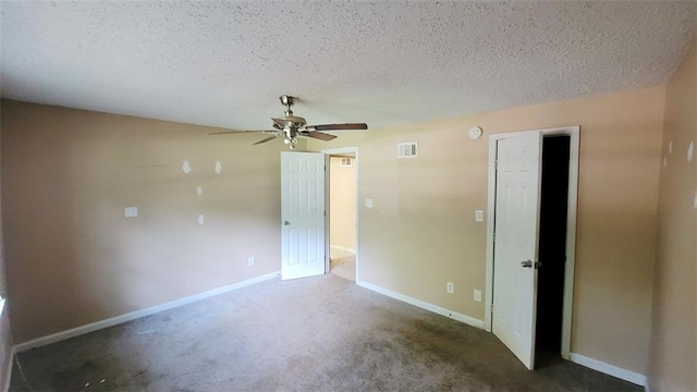 spare room featuring ceiling fan, dark carpet, and a textured ceiling