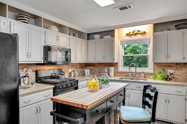 kitchen featuring black appliances, butcher block counters, and white cabinetry