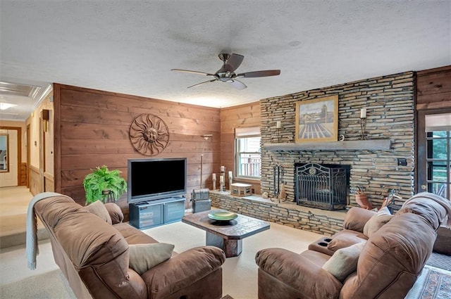 carpeted living room featuring wood walls, a wealth of natural light, and a stone fireplace