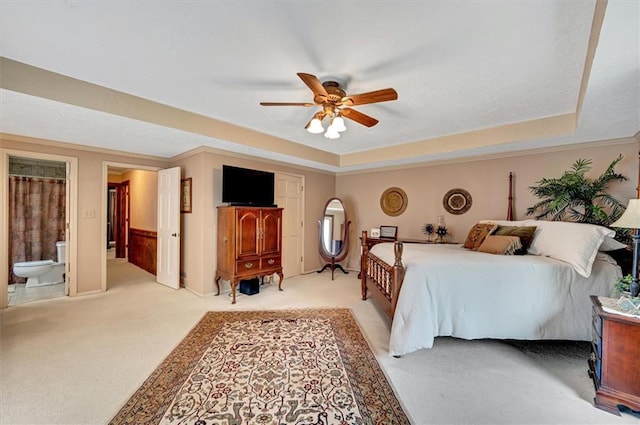 bedroom with a tray ceiling, ceiling fan, ensuite bathroom, and carpet