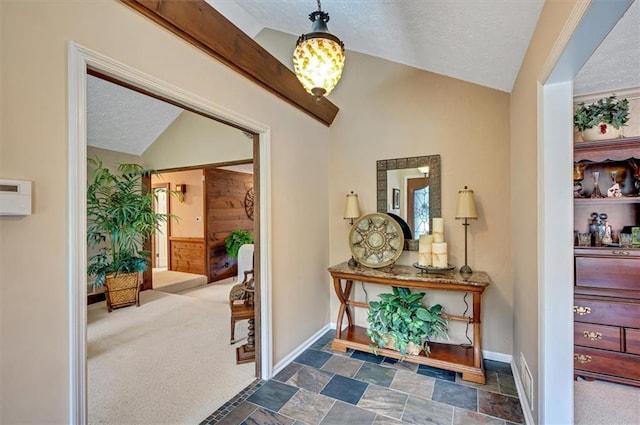 hallway featuring vaulted ceiling, a textured ceiling, and dark carpet