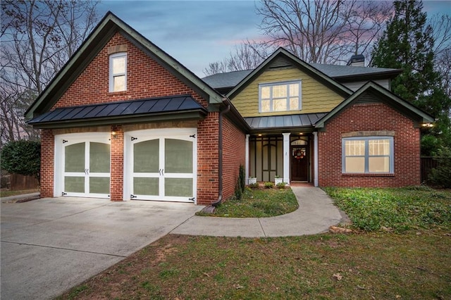 view of front of house featuring french doors, brick siding, a chimney, concrete driveway, and a standing seam roof