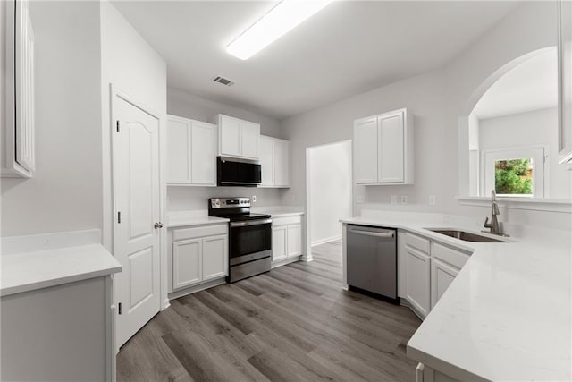 124 Oakmont Dr, Dawsonville, GA 30534 - kitchen featuring stainless steel appliances, a sink, arched walkways, and white cabinets
