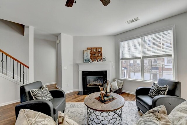 living room with ceiling fan, a high end fireplace, and dark hardwood / wood-style floors