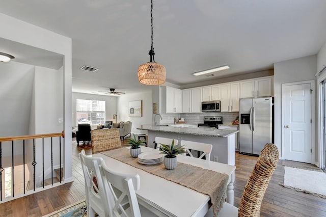 dining space with ceiling fan, sink, and dark wood-type flooring