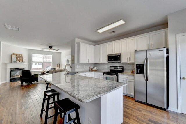 kitchen featuring white cabinets, light wood-type flooring, kitchen peninsula, and appliances with stainless steel finishes