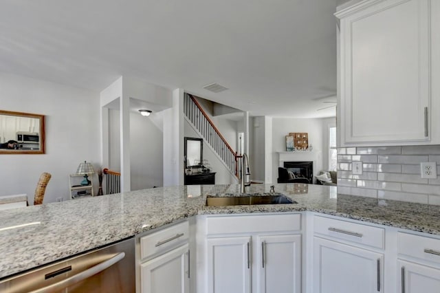 kitchen with light stone counters, stainless steel appliances, white cabinetry, and sink