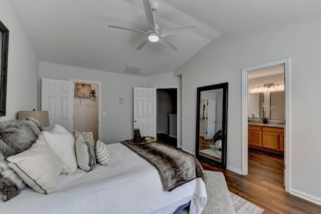 bedroom with ceiling fan, dark hardwood / wood-style floors, ensuite bathroom, vaulted ceiling, and a closet