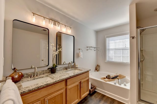 bathroom featuring vanity, hardwood / wood-style floors, and plus walk in shower