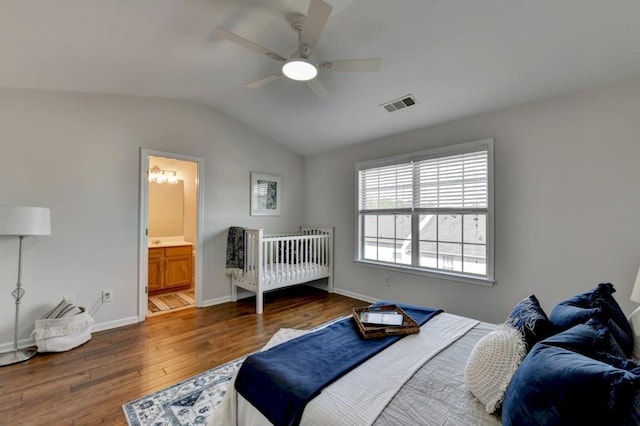 bedroom with ceiling fan, dark hardwood / wood-style flooring, connected bathroom, and vaulted ceiling