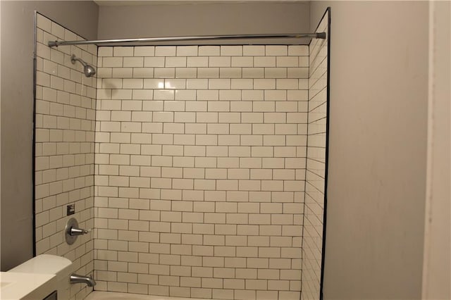 room details featuring toilet and tiled shower / bath