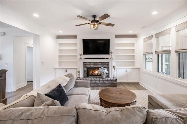 living room featuring light hardwood / wood-style floors, ceiling fan, and a fireplace