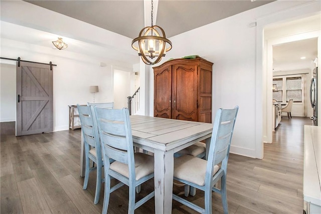 dining area featuring an inviting chandelier, light hardwood / wood-style floors, and a barn door