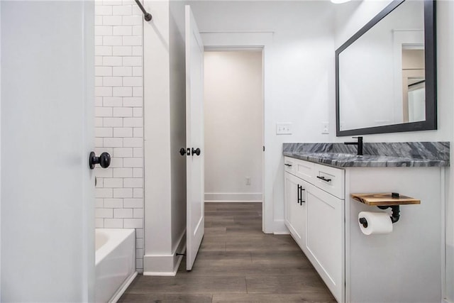 bathroom with tiled shower / bath combo, hardwood / wood-style floors, and vanity