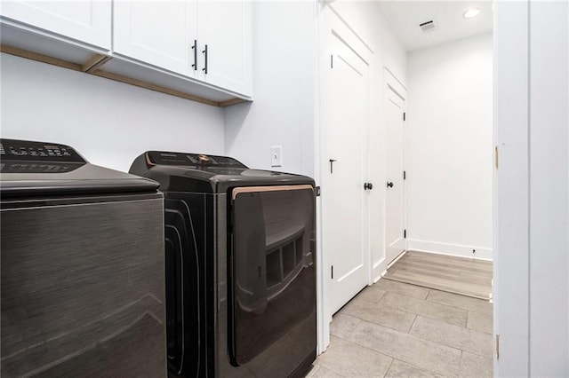 washroom featuring light tile patterned flooring, washing machine and clothes dryer, and cabinets