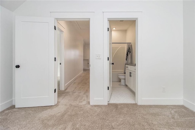 unfurnished bedroom featuring a walk in closet, a closet, light colored carpet, and connected bathroom