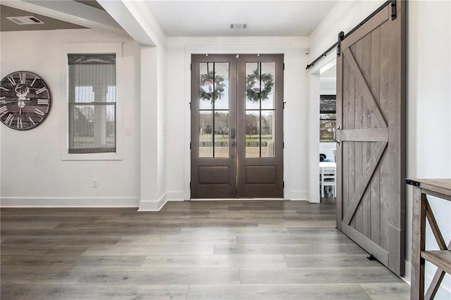 entrance foyer with a barn door, french doors, and hardwood / wood-style floors