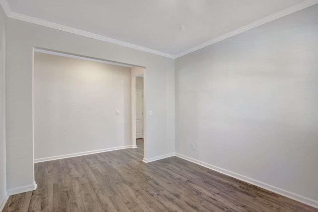 unfurnished room with crown molding, baseboards, and wood finished floors